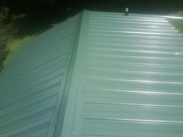 New green metal panels meeting at the ridge of a roof — Flat Roof Repair work by our crew in Larchmont