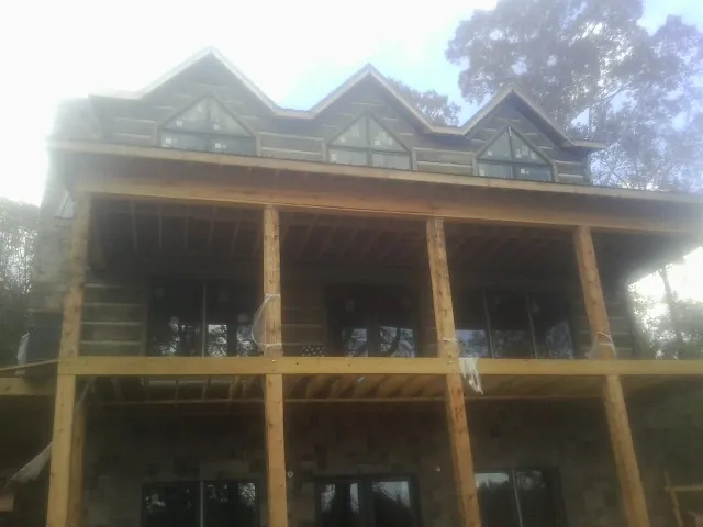 Dormers and porch framing on a large log home under construction — Roof Coating work by our crew in Larchmont