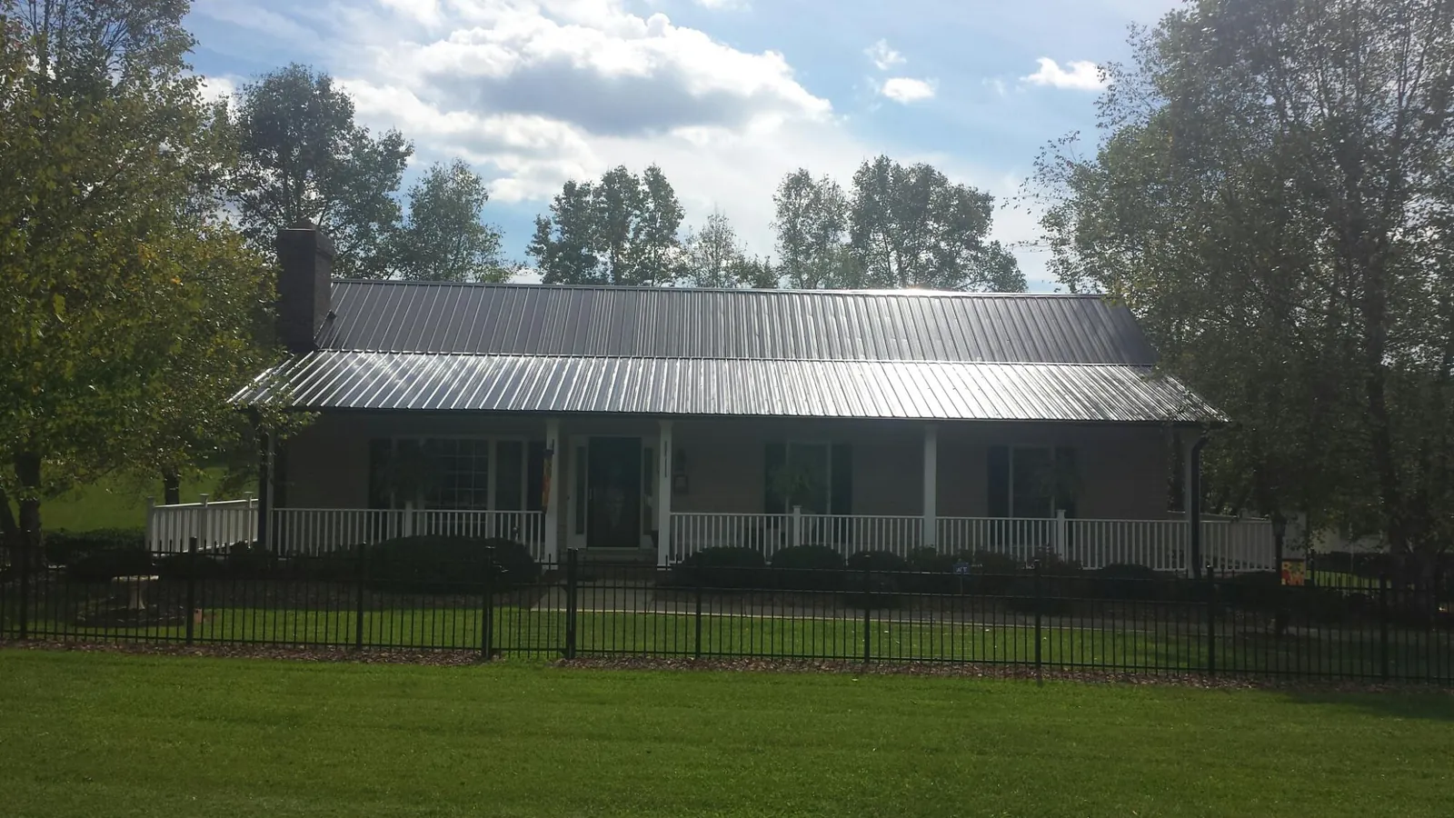 Gray metal roof on a brick ranch with a full width front porch — Gutter Guard Installation work by our crew in Larchmont