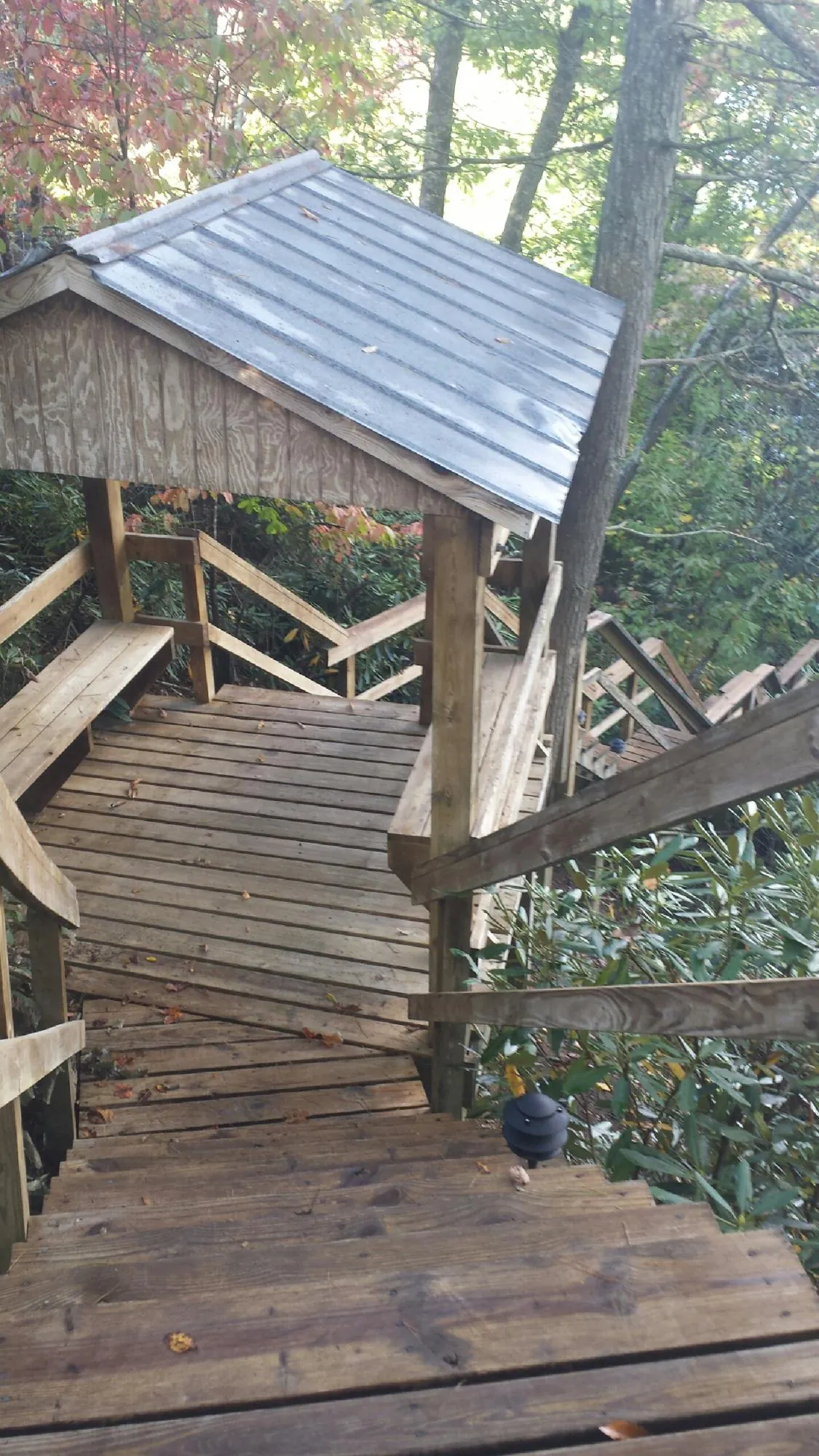 Metal roofed shelter over wooden steps on a wooded walkway — Skylight Repair & Installation work by our crew in Larchmont