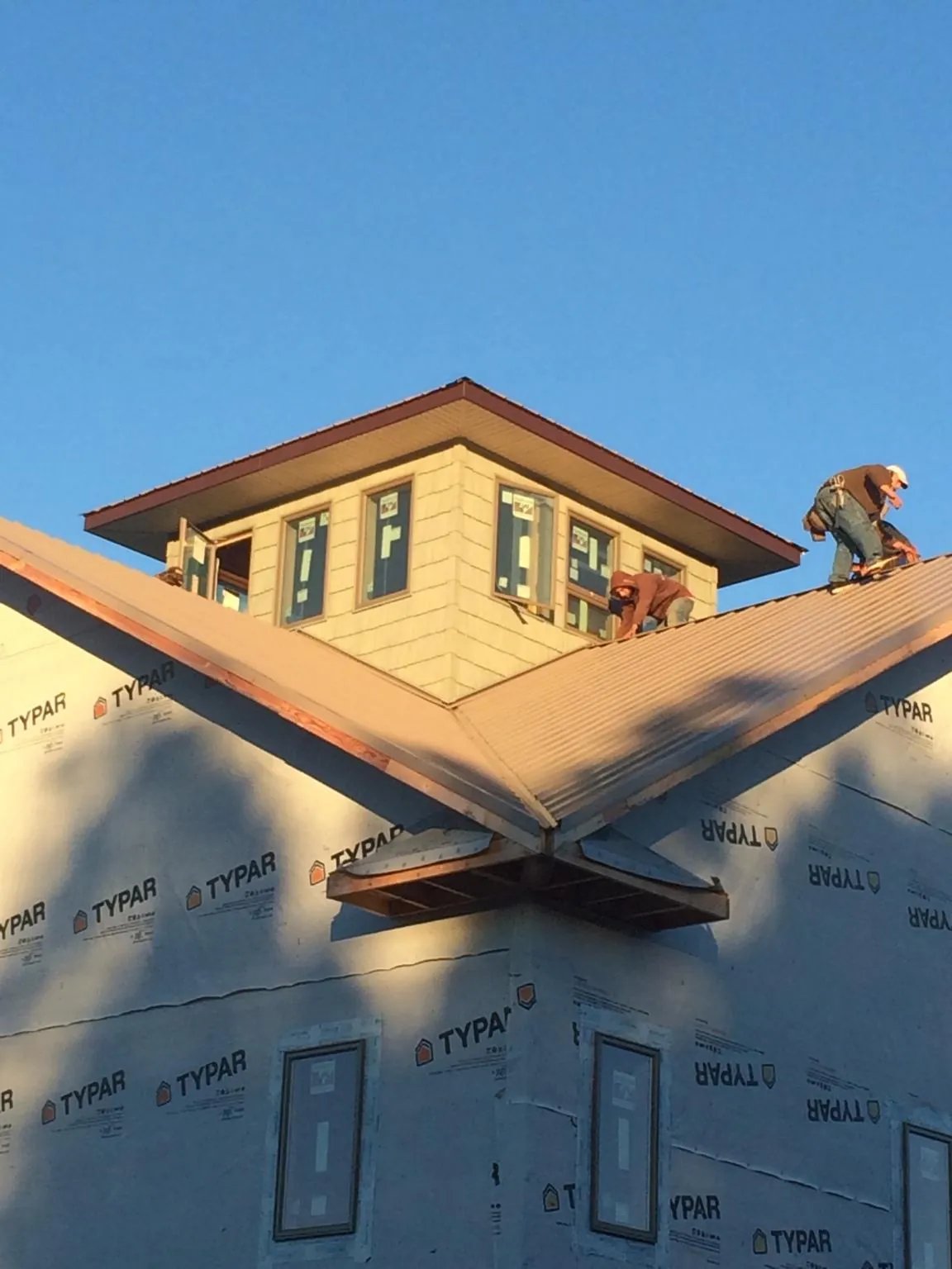 Roofers working around a rooftop cupola on a new metal roof at sunset — Roof Waterproofing in Larchmont by Roofing Brothers